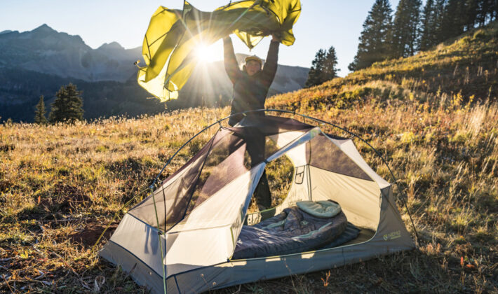 photo of a person preparing a sleeping bag and tent