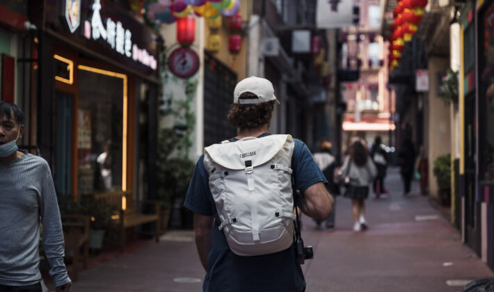 photo of someone walking on a street with a backpack